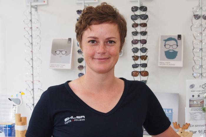 Nadine Thomsen steht vor Brillen in unserem Fachgeschäft in der Mürwiker Straße in Flensburg.